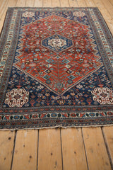 Angled perspective of a vintage Abadeh rug highlighting its red and blue hexagonal medallion design.