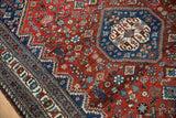 Angled view of the vintage Abadeh rug's blue serrated medallion and intricate red floral field.