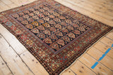 Antique Caucasian rug's left side with worn pile, geometric botehs, and crab border.