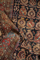 Antique Caucasian rug with geometric boteh field, pawn border, and visible wear.