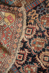 Antique Caucasian rug close-up showing crab motif, worn pile, exposed foundation, and fringe detail.