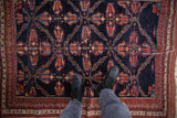 A person's perspective showing the scale of an antique Afshar rug's intricate lattice design.