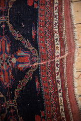 Corner detail of an antique Afshar showing geometric borders and wear to the knot heads.