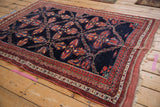Full angled view of an antique Afshar rug's intricate vine lattice and multi-banded border.