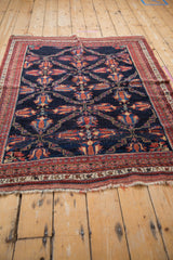 Angled view of an antique Persian Afshar rug, featuring a navy and red geometric lattice design.