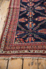 Low-angle view of an antique Afshar's intricate red border alongside its low-pile navy field.