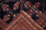 Folded corner of a fine Afshar rug showing the hand-knotted back and detailed madder red border.