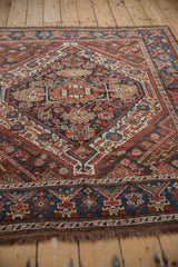 Hand-knotted vintage Kamseh rug detail showing geometric pinwheel motifs in navy, chestnut, ivory, and saffron.