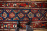 A top-down view of the detailed geometric medallions and rich color palette on an antique Caucasian runner.