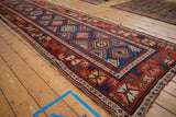 Angled perspective of an antique Caucasian runner with its geometric guls in a repeating lattice.