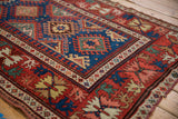 Close view of the geometric starburst guls on a sapphire blue field and madder red border.