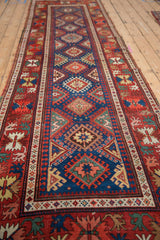 A long perspective of an antique Caucasian runner's repeating geometric guls and starburst motifs.