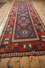 Angled perspective of an antique Caucasian runner highlighting its repeating geometric pattern and colorful border.