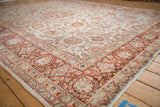 Corner view of a vintage Meshed carpet highlighting the low-pile texture and copper floral border.