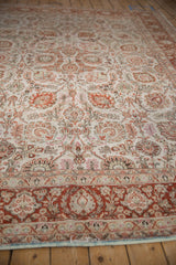 Angled view down the length of a distressed Meshed carpet, showing its ivory field and floral pattern.