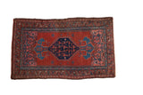 Vintage Kurdish Bijar rug with a navy diamond medallion and Herati motifs on an abrashed cherry red field.