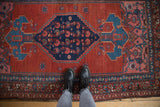 Vintage Kurdish Bijar rug underfoot, showing the scale of its Herati border and cherry red field.
