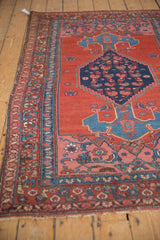 Angled view of a vintage Kurdish Bijar rug, detailing the intact side cord and complex geometric border.