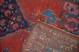 Folded corner of a vintage Kurdish rug showing the cherry red pile and hand-knotted back.