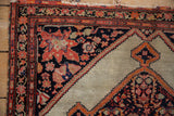 Antique Malayer rug corner showing navy spandrels with expressive leaves, blossoms, and birds.