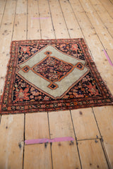 Angled view of an antique square Malayer rug with a central ivory diamond medallion.