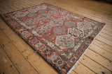 Angled view of a distressed Persian Bakhtiari rug showing its allover geometric design and rustic tones.