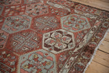 Close-up of the serrated leaf border and worn texture on a vintage Baktiari rug.
