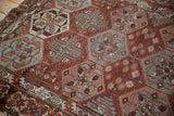 Corner detail of a vintage Bakhtiari rug showing its serrated border and worn floral motifs.