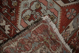 Folded corner of a distressed Baktiari rug showing its hand-knotted back and secured ivory fringe.