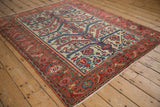 An antique Fine Malayer rug's sprawling vine pattern and Herati border viewed from an angle.