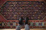 Kurdish Hamadan rug corner shows geometric vinery lattice in navy, red, gold, green.