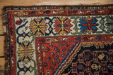 Hand-knotted geometric flowers and crab border in madder red, indigo, ivory.