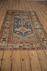 Worn vintage Caucasian rug with navy blue, beige, and rust geometric mahi-mahi motifs.