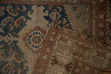 Worn vintage Caucasian rug detail: navy, beige, rust patterns, exposed foundation, frayed edge.