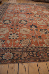 Angled view of a vintage Tabriz carpet's grand floral pattern in rust and charcoal navy.