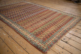 The dynamic, repeating boteh pattern of a fine antique Bijar carpet viewed from an angled perspective.