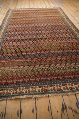 A full-length angled perspective on an antique Bijar carpet, highlighting its dynamic rows of botehs.