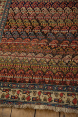 Angled view of an antique Bijar showing the recessed pile and richly colored rows of boteh motifs.