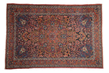 Vintage Persian Isfahan rug with a scalloped medallion over a floral field of red, sapphire blue, and gold.