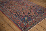 Angled view of a vintage Isfahan rug with detailed pinwheel florals and botehs in red and sapphire blue.