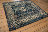 Angled view of a vintage Persian Bijar square rug with a navy charcoal and ivory geometric pattern.