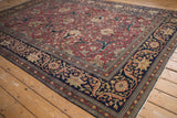 Corner detail of an antique Tabriz carpet with floral arabesques on the red field and navy border.