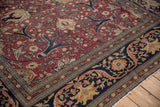 Detailed corner of a fine Tabriz carpet showing its navy border and red field with expressive floral arabesques.