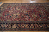Perspective view of an antique Tabriz carpet showing the dense floral pattern and complex navy borders.