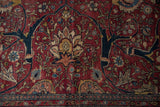 Close-up of expressive floral arabesques and scrolling vinery on a red antique Tabriz carpet.