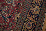 Floral arabesques in the navy border and scrolling vinery in the red field of this antique Tabriz.