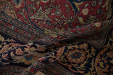 Detailed floral arabesques in cochineal red and navy blue on a draped antique Tabriz carpet.