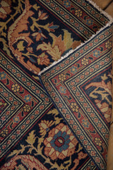 Corner detail of an antique Tabriz carpet folded to show the intricate border and woven pile.