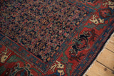 Brick red border with mythical antlered animals and dusty navy Herati field pattern.