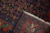 Mythical animal border and cream fringe on a folded vintage Persian Bijar rug.